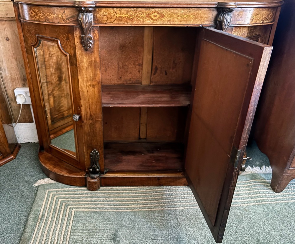 A Victorian walnut side cabinet featuring floral marquetry inlays, three glazed doors, carved corbels, and a shaped serpentine front. View IV