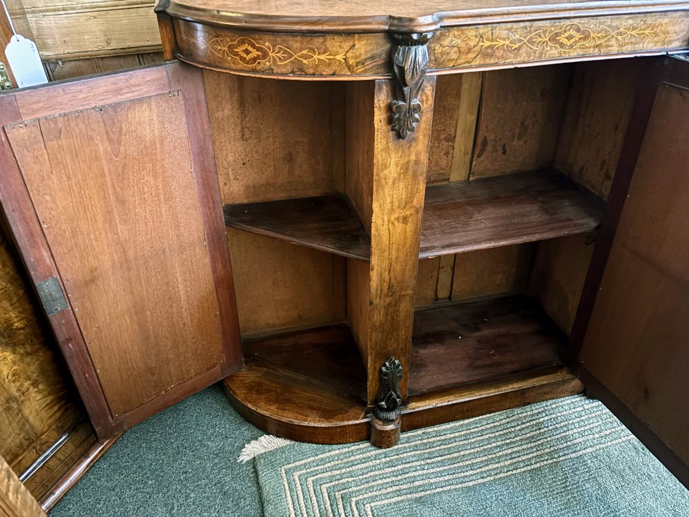 A Victorian walnut side cabinet featuring floral marquetry inlays, three glazed doors, carved corbels, and a shaped serpentine front. View V
