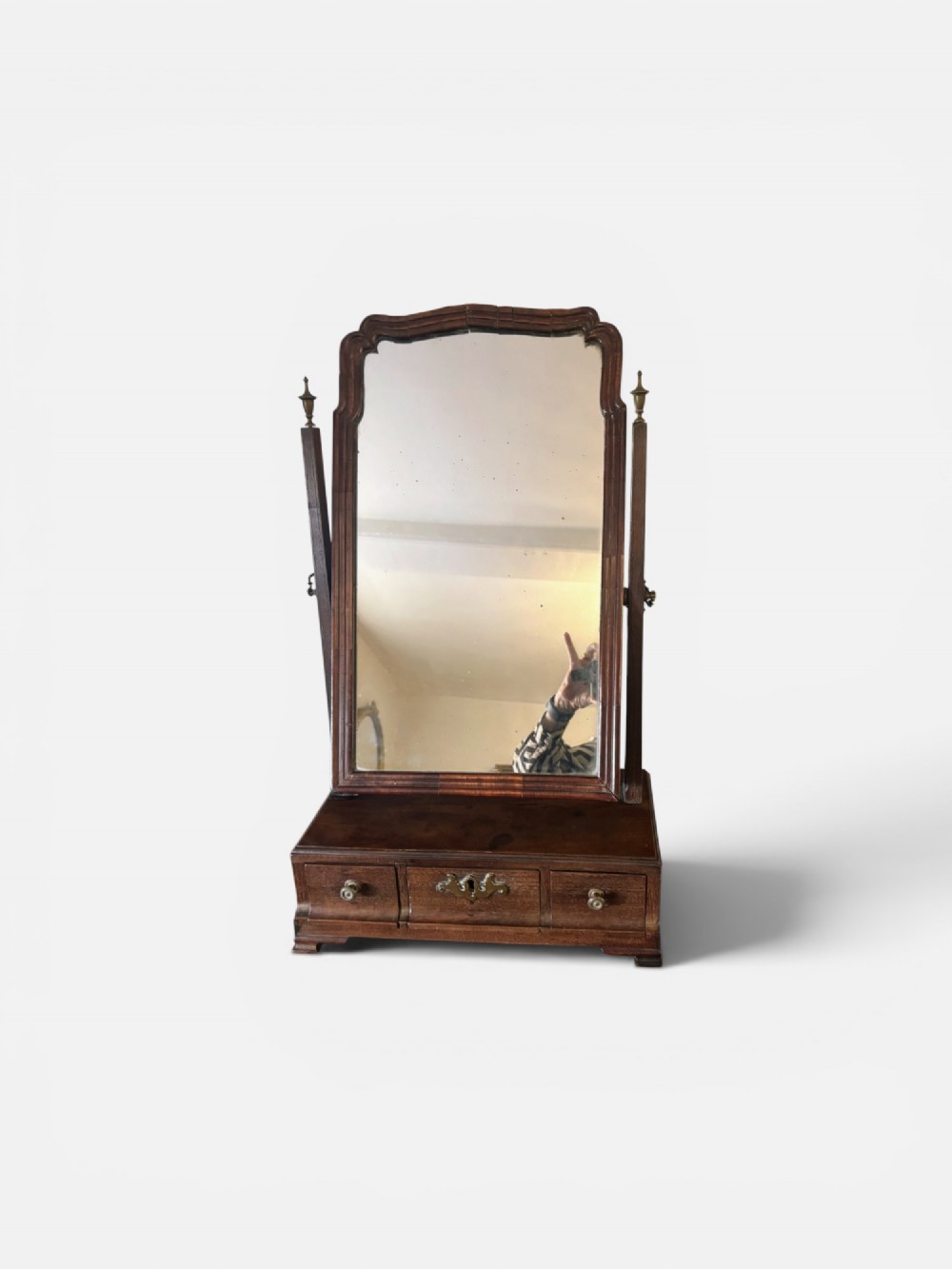 A George III mahogany toilet mirror featuring an adjustable swing plate mounted above a plinth base with three drawers and brass hardware.