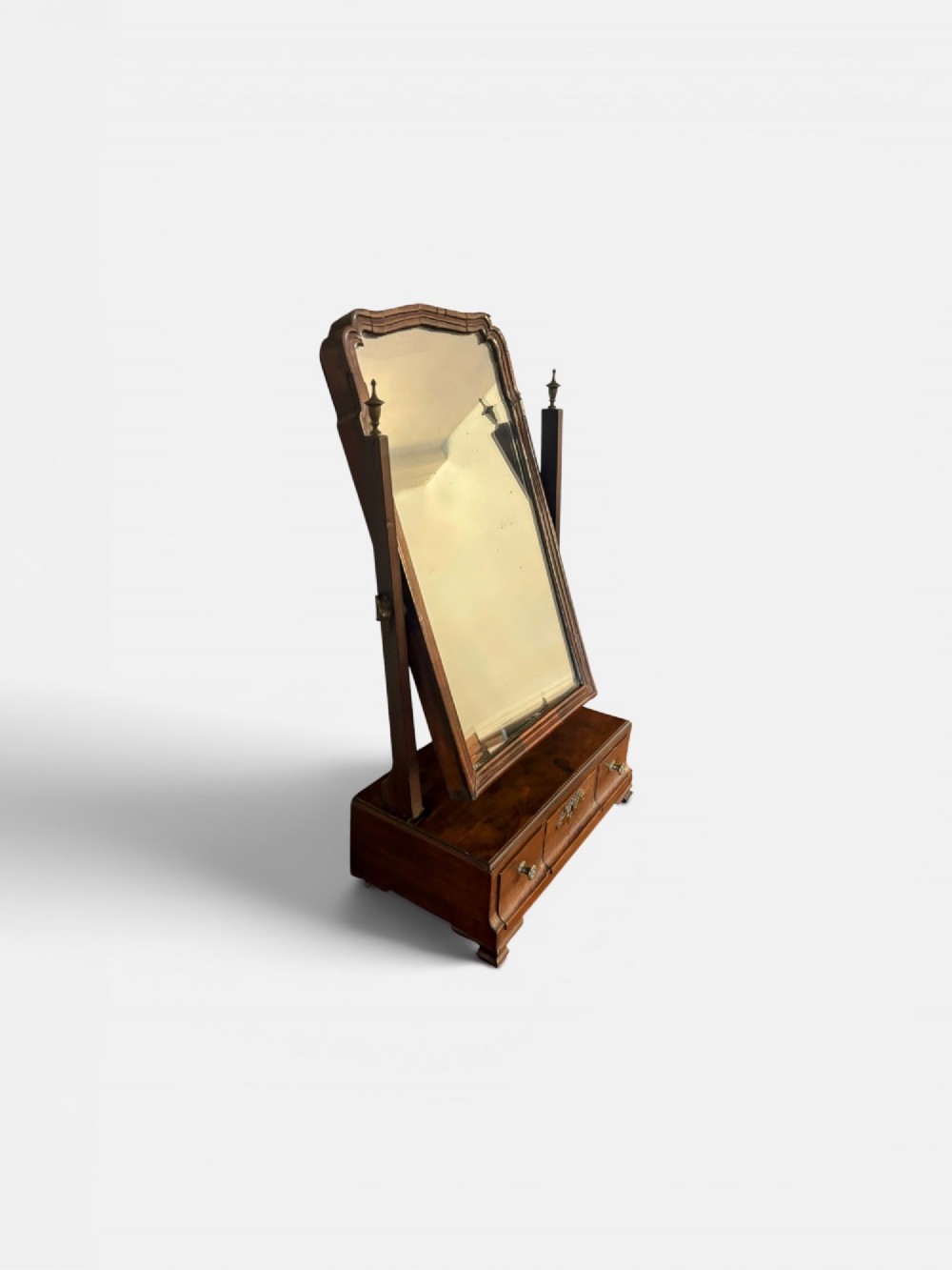 A George III mahogany toilet mirror featuring an adjustable swing plate mounted above a plinth base with three drawers and brass hardware. View III