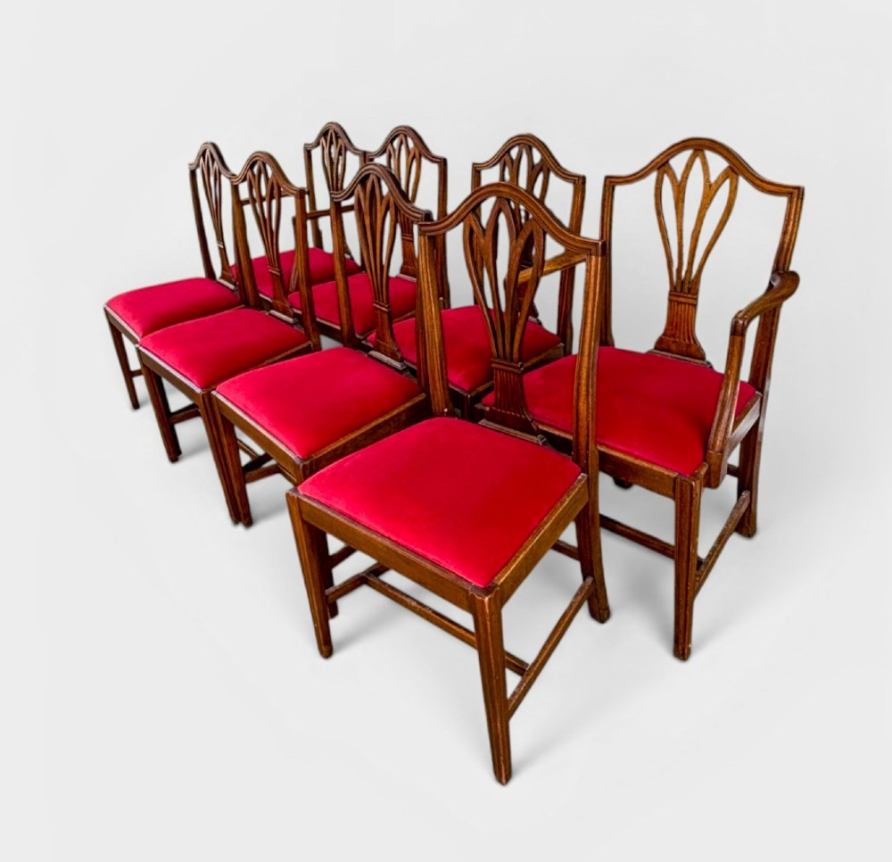 A set of eight George III mahogany dining chairs featuring carved wheat sheaf back splats and red velvet seats. View II