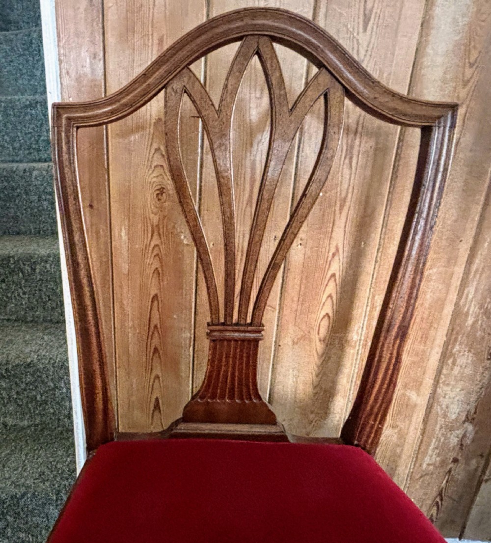 A set of eight George III mahogany dining chairs featuring carved wheat sheaf back splats and red velvet seats. View XI