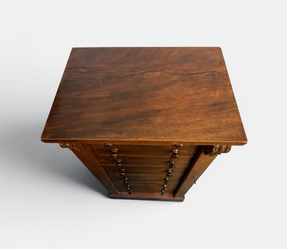 A tall Victorian walnut Wellington chest featuring seven stacked drawers, a right-hand locking stile, carved corner corbels, and turned wooden handles on a plinth base. View II