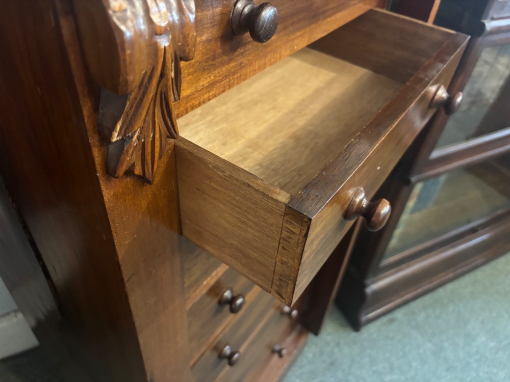 A tall Victorian walnut Wellington chest featuring seven stacked drawers, a right-hand locking stile, carved corner corbels, and turned wooden handles on a plinth base. View VII