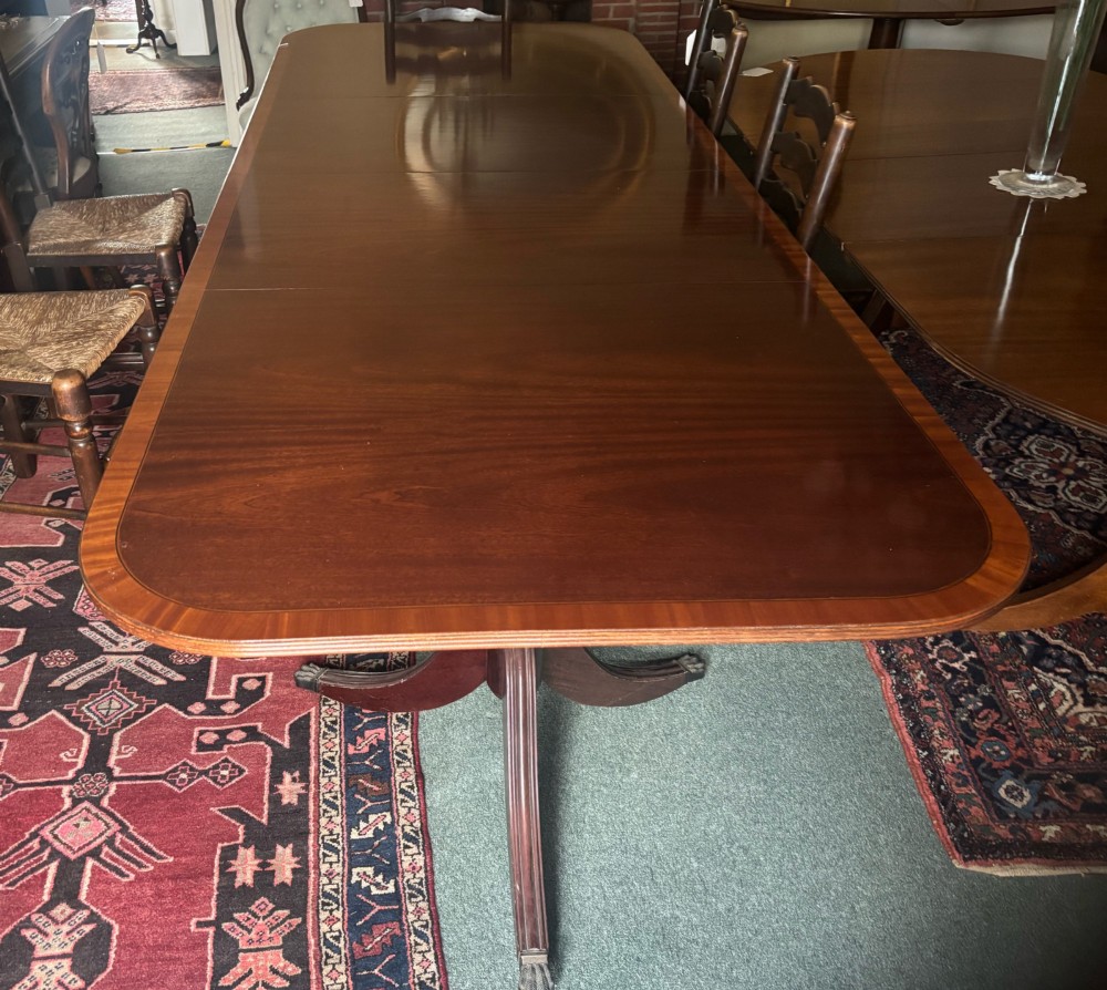 A Regency style mahogany twin pillar dining table featuring a crossbanded top and splayed quadruped feet on brass castors. View V