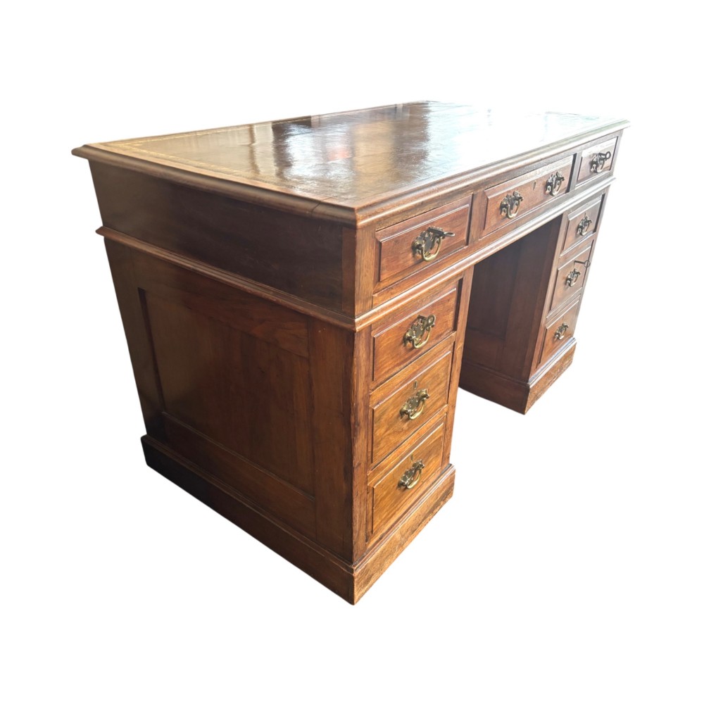 A Victorian walnut pedestal desk featuring nine drawers with brass handles and a gilt-tooled leather writing top. View V