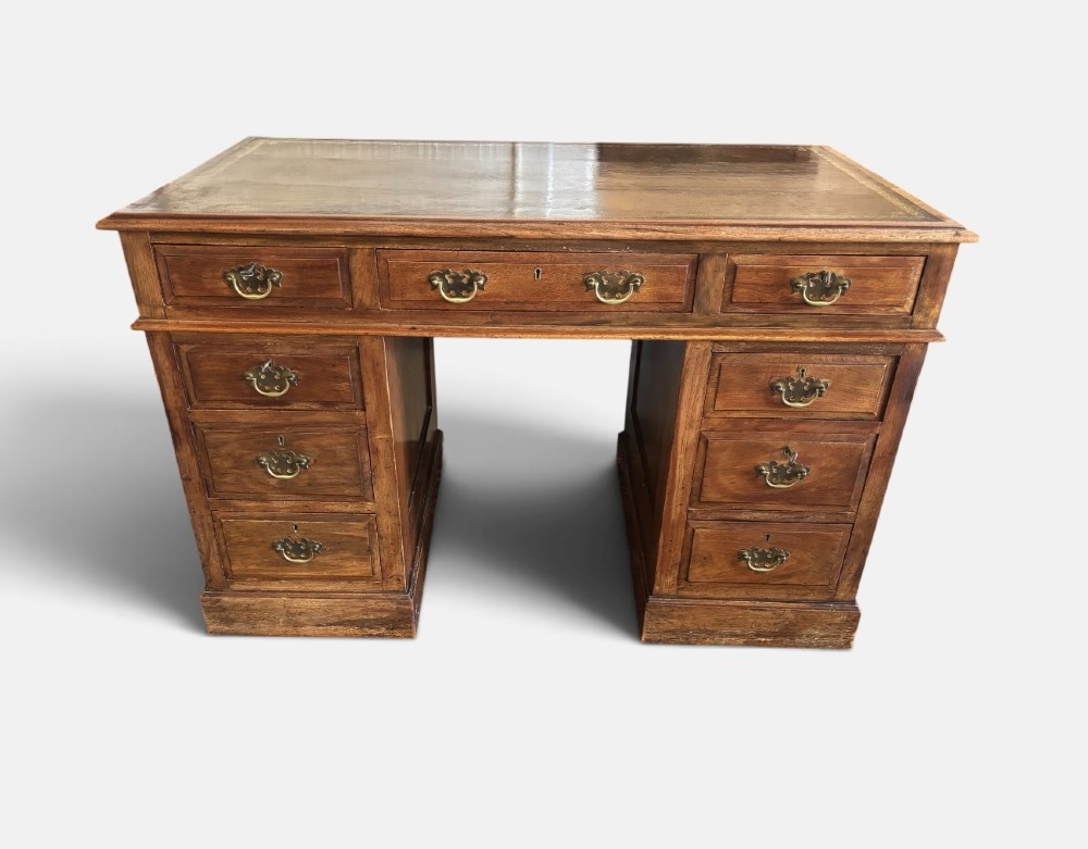 A Victorian walnut pedestal desk featuring nine drawers with brass handles and a gilt-tooled leather writing top. View VII