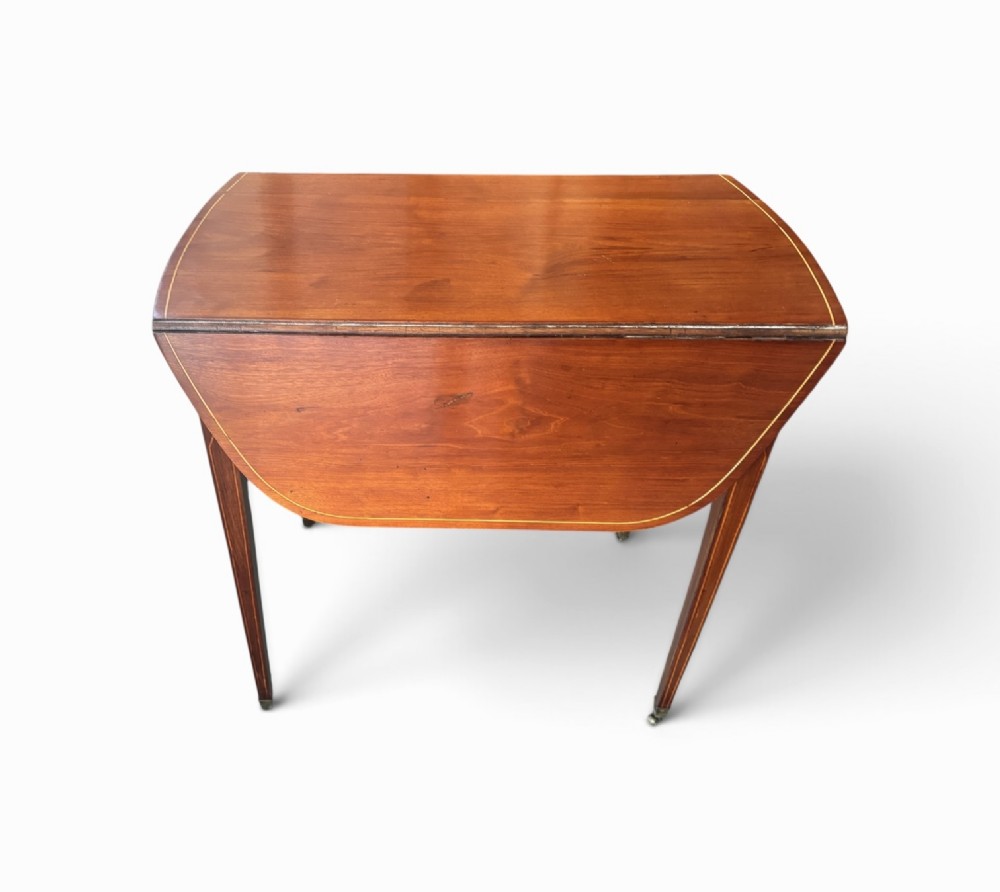 A Regency mahogany oval supper table with twin drop leaves, fine boxwood inlay, a central frieze drawer, and square tapered legs on brass castors. View III