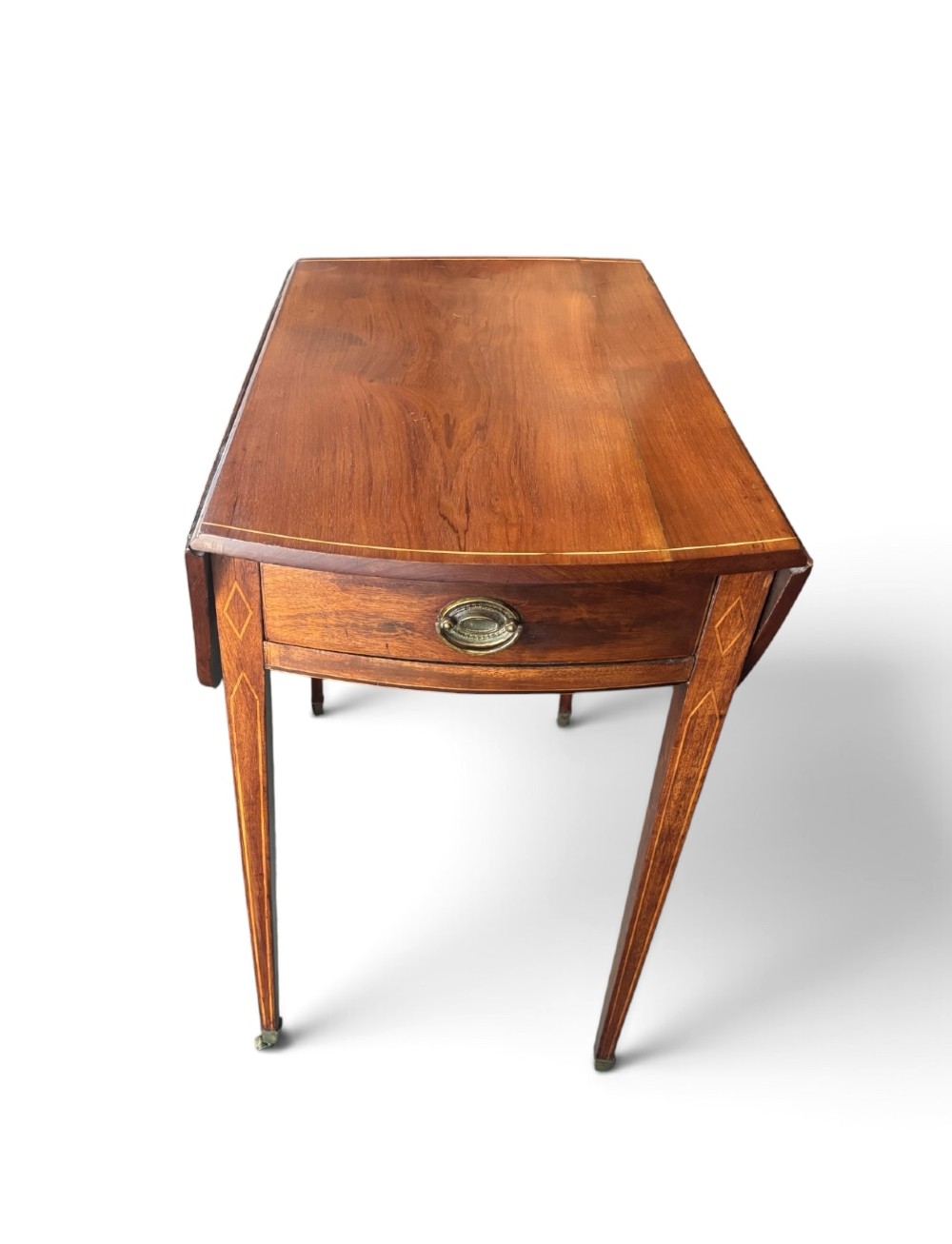 A Regency mahogany oval supper table with twin drop leaves, fine boxwood inlay, a central frieze drawer, and square tapered legs on brass castors. View IV