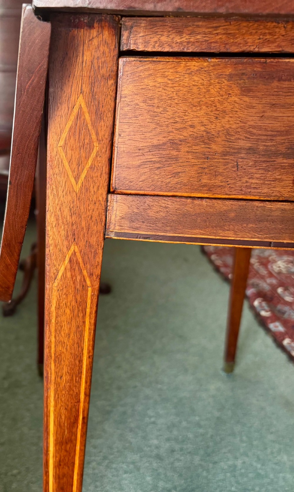 A Regency mahogany oval supper table with twin drop leaves, fine boxwood inlay, a central frieze drawer, and square tapered legs on brass castors. View VI