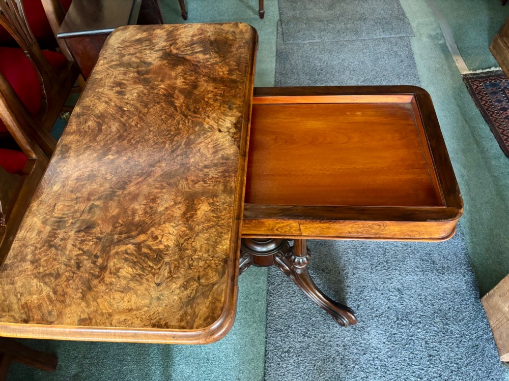 A Victorian rectangular flip-top card table made from figured walnut wood, featuring rounded corners and a carved quad-form pedestal base. View V