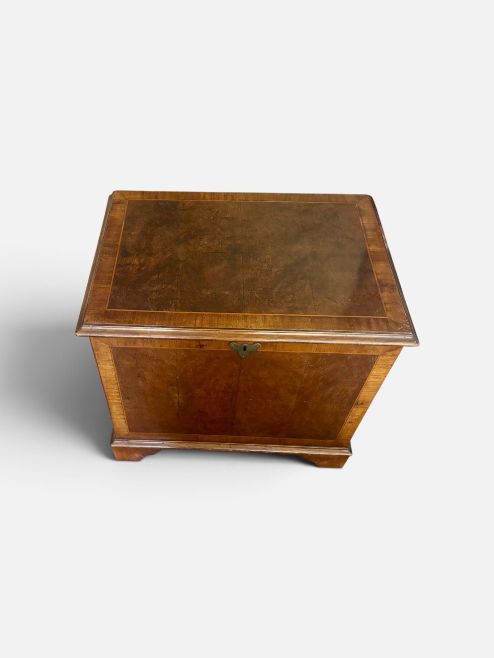 A small antique figured walnut coffer featuring crossbanded borders, a brass escutcheon, and bracket feet. View II