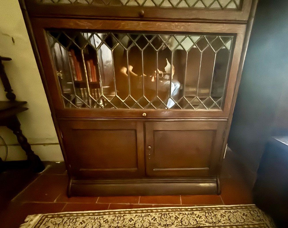 An early twentieth-century dark oak sectional barrister bookcase featuring four leaded glass door tiers above a two-door panelled cabinet base. View III