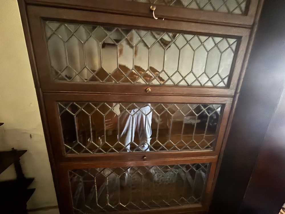 An early twentieth-century dark oak sectional barrister bookcase featuring four leaded glass door tiers above a two-door panelled cabinet base. View IV