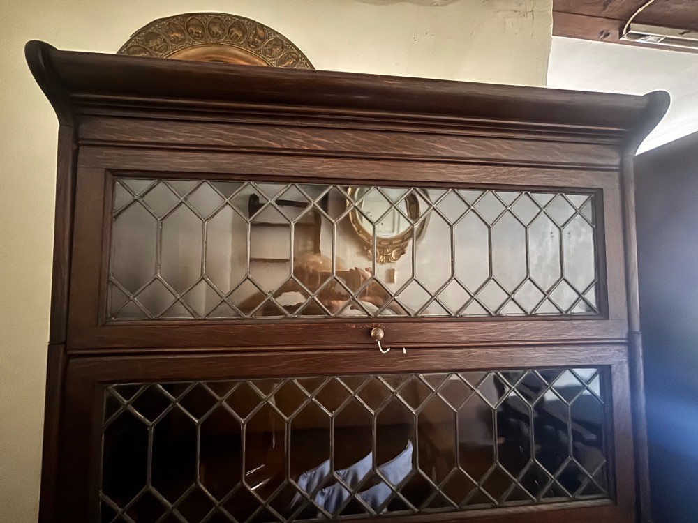 An early twentieth-century dark oak sectional barrister bookcase featuring four leaded glass door tiers above a two-door panelled cabinet base. View V