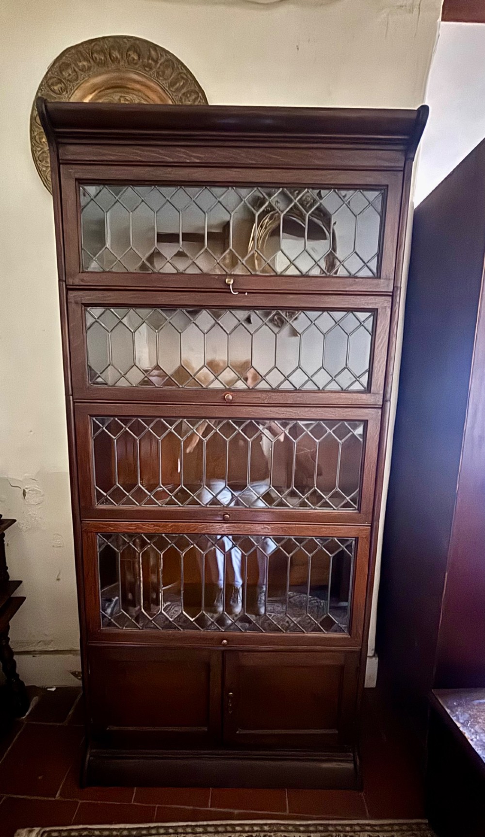 An early twentieth-century dark oak sectional barrister bookcase featuring four leaded glass door tiers above a two-door panelled cabinet base. View VI