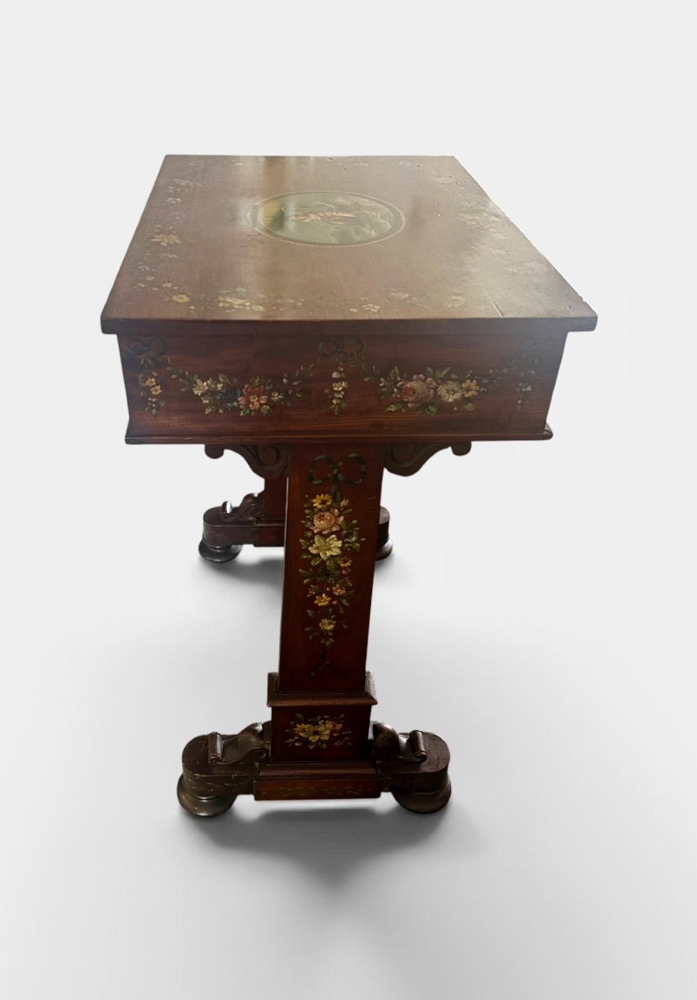 An early Victorian mahogany side table featuring hand-painted floral garlands across the surface and drawer, supported by trestle legs and a turned central stretcher. View II