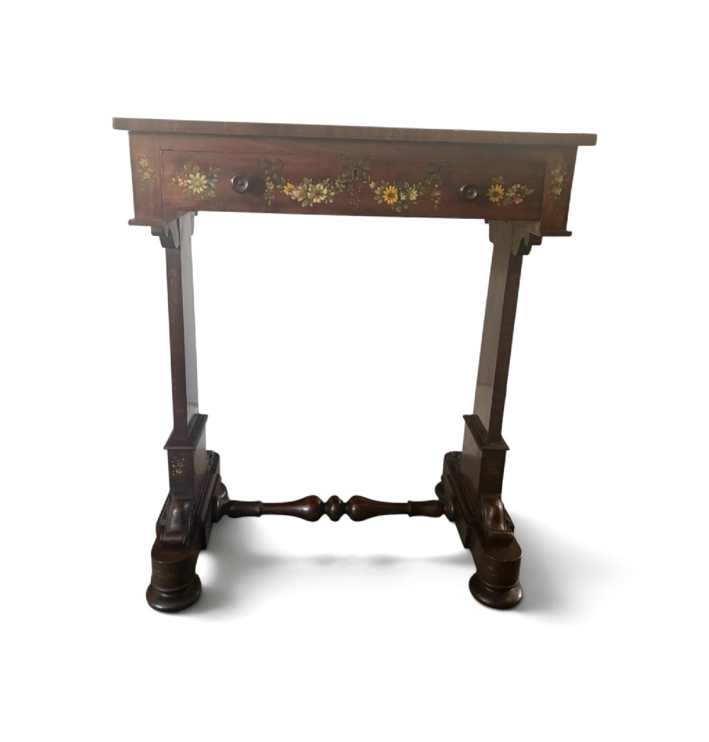 An early Victorian mahogany side table featuring hand-painted floral garlands across the surface and drawer, supported by trestle legs and a turned central stretcher. View V