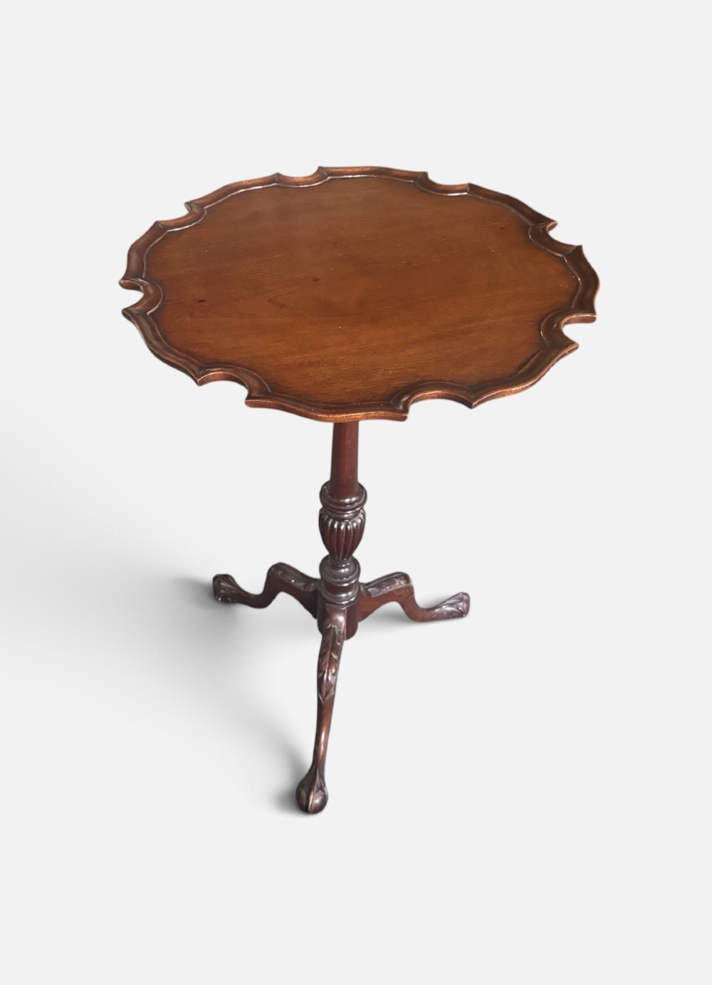 A small mahogany tripod table featuring a raised scalloped piecrust top supported by a carved central pedestal and three cabriole legs. View II