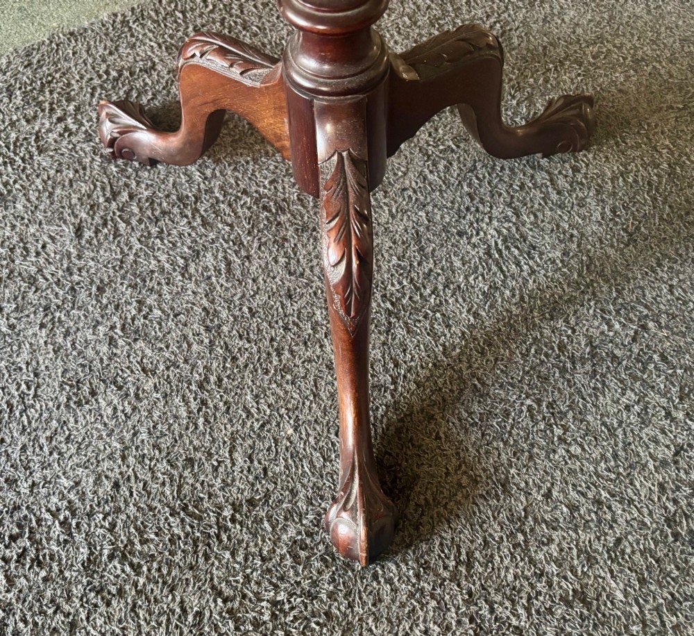 A small mahogany tripod table featuring a raised scalloped piecrust top supported by a carved central pedestal and three cabriole legs. View V