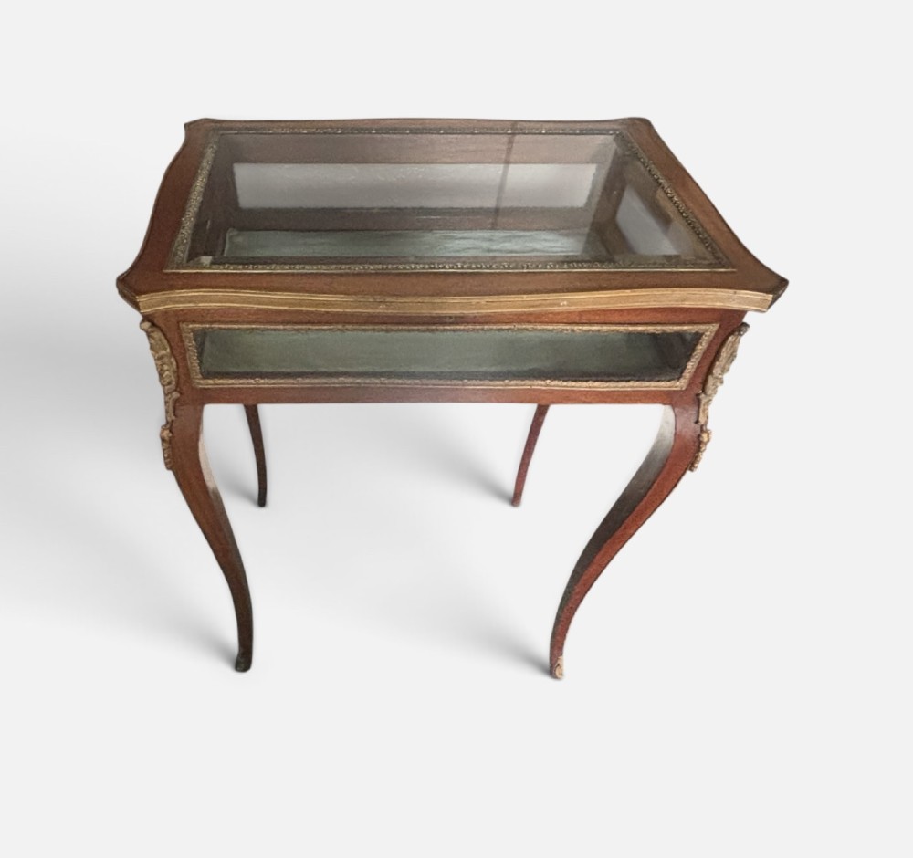 A 19th-century walnut vitrine display table featuring glass side panels, decorative metal mounts, and slender cabriole legs.
