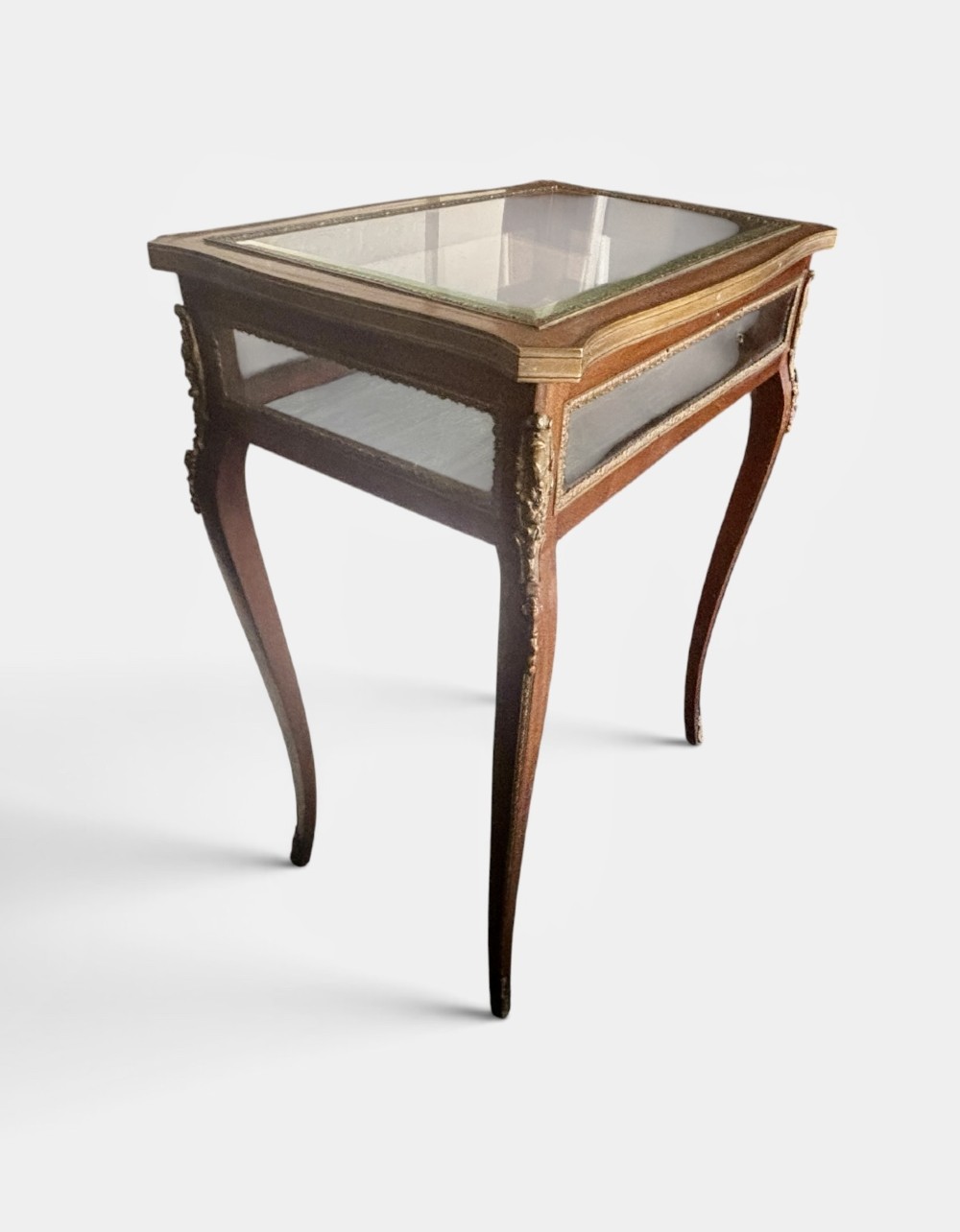 A 19th-century walnut vitrine display table featuring glass side panels, decorative metal mounts, and slender cabriole legs. View VI