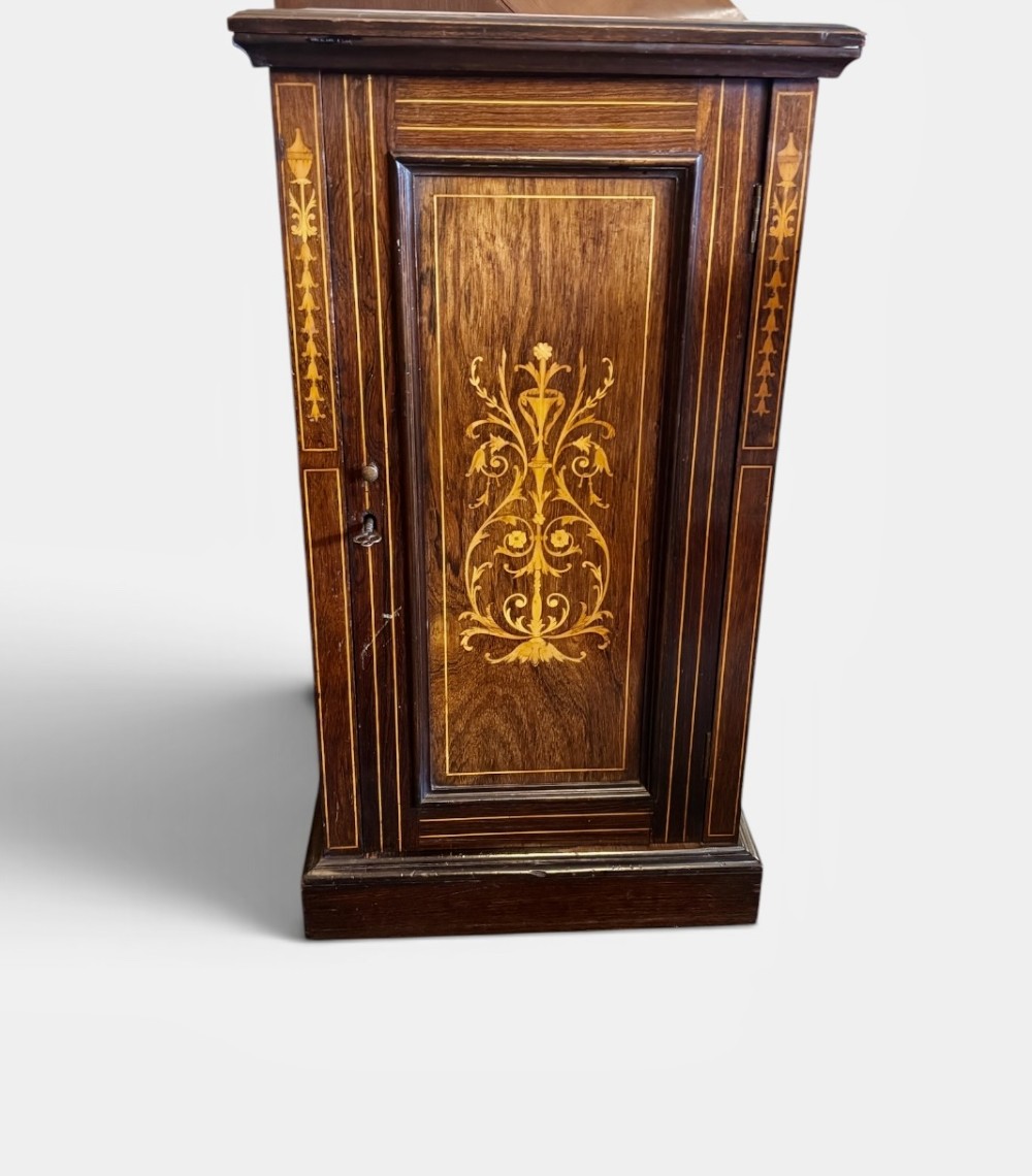 A tall, narrow Victorian rosewood cabinet featuring intricate floral marquetry inlay on the single panelled door and side pilasters.