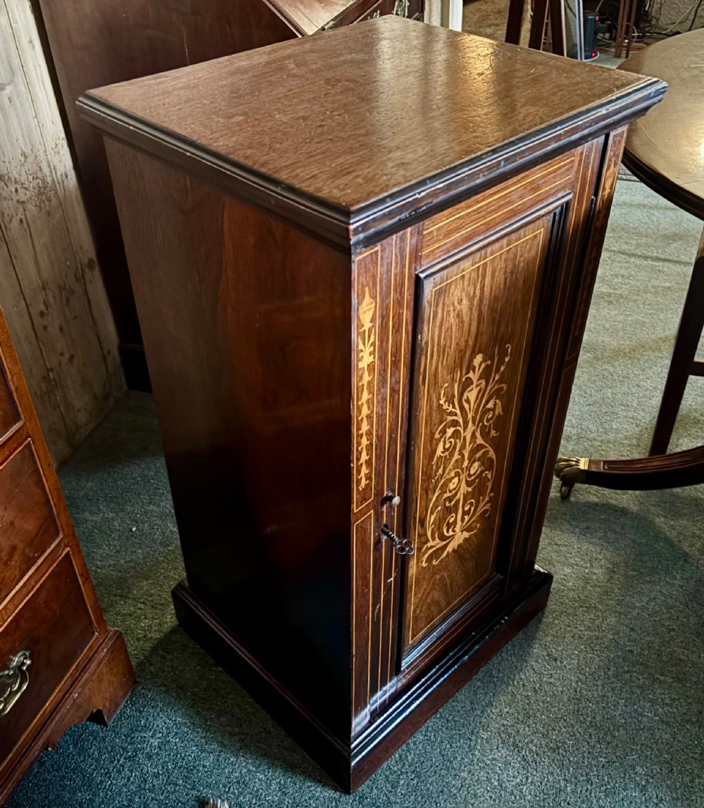 A tall, narrow Victorian rosewood cabinet featuring intricate floral marquetry inlay on the single panelled door and side pilasters. View IV