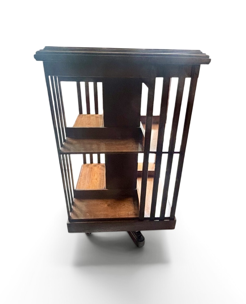 An Edwardian walnut revolving bookcase featuring two tiers of open shelving, vertical slatted sides, and a moulded top edge. View II