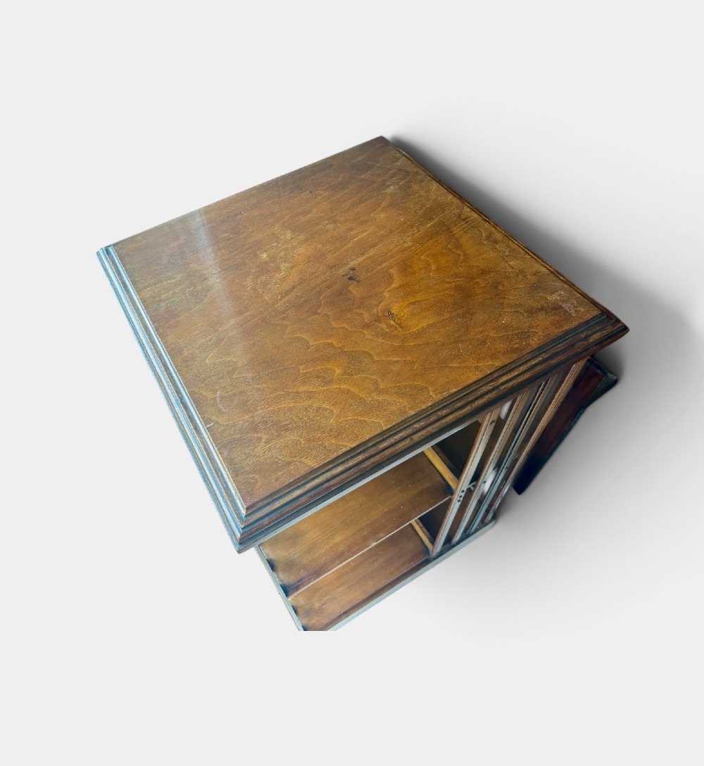 An Edwardian walnut revolving bookcase featuring two tiers of open shelving, vertical slatted sides, and a moulded top edge. View IV