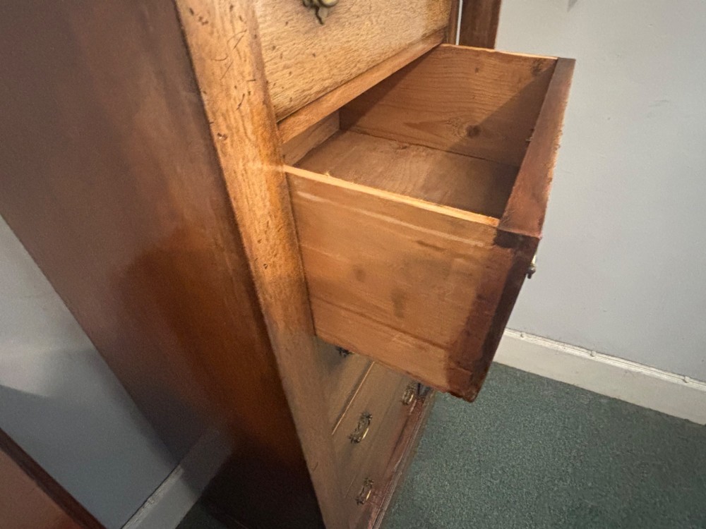 A tall, narrow Edwardian mahogany Wellington chest featuring five graduated drawers with brass handles and a hinged side locking bar on a plinth base. View V
