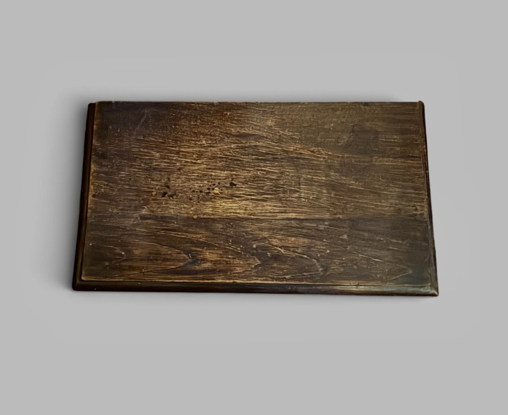 A small dark oak coffer with a hinged rectangular top, shaped fielded front panel, and solid side supports. View III