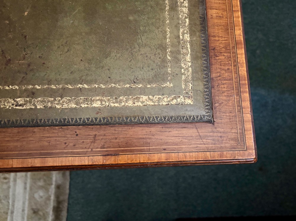 An Edwardian mahogany writing table featuring a green leather insert surface, satinwood crossbanding, one long drawer, and square tapered legs. View IV