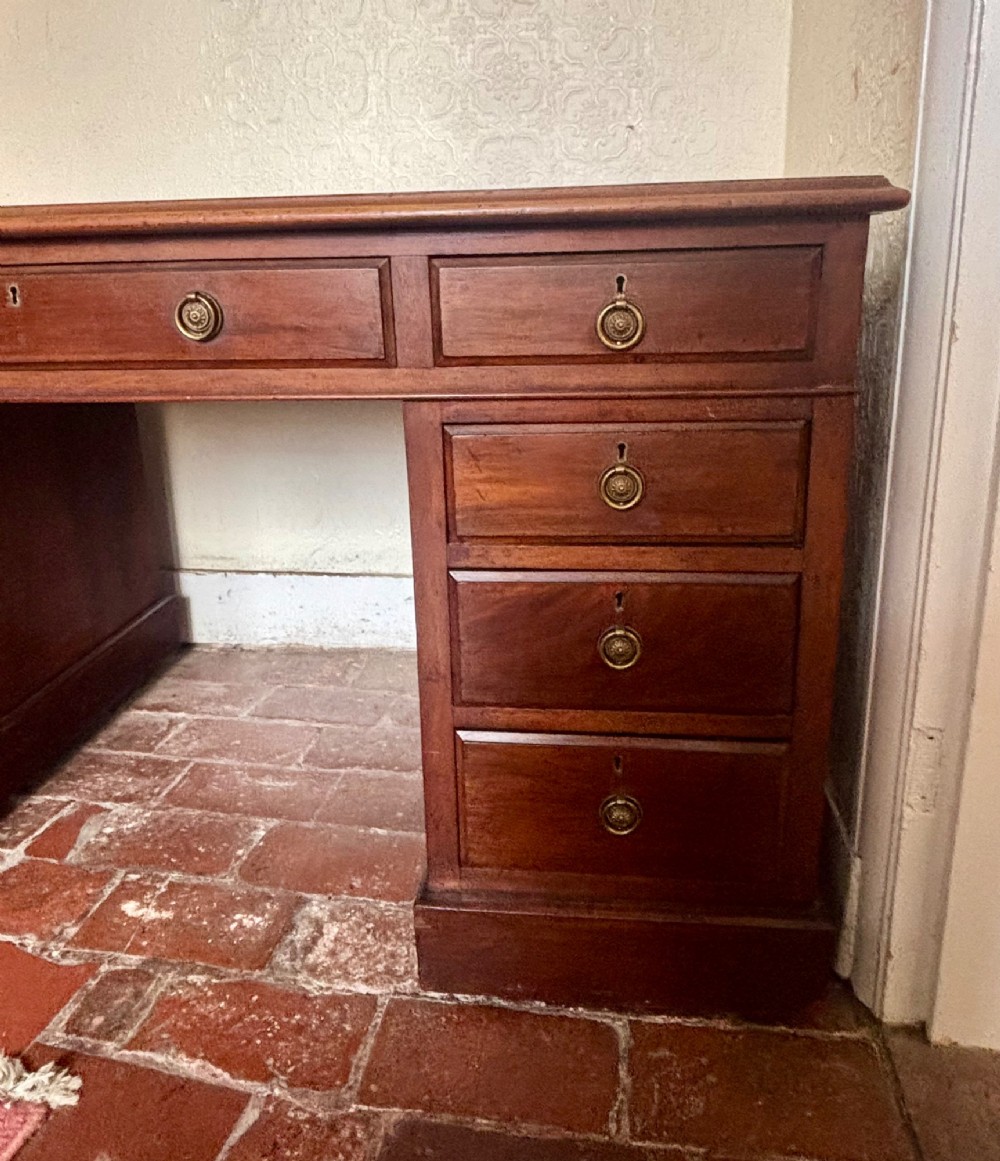 A large Edwardian mahogany pedestal desk featuring nine drawers with circular brass ring handles and a flat plinth base. View VII