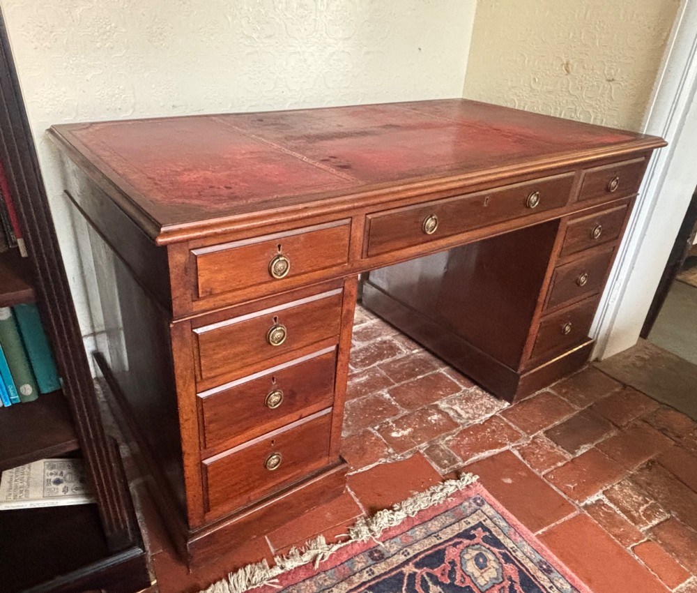 A large Edwardian mahogany pedestal desk featuring nine drawers with circular brass ring handles and a flat plinth base. View X