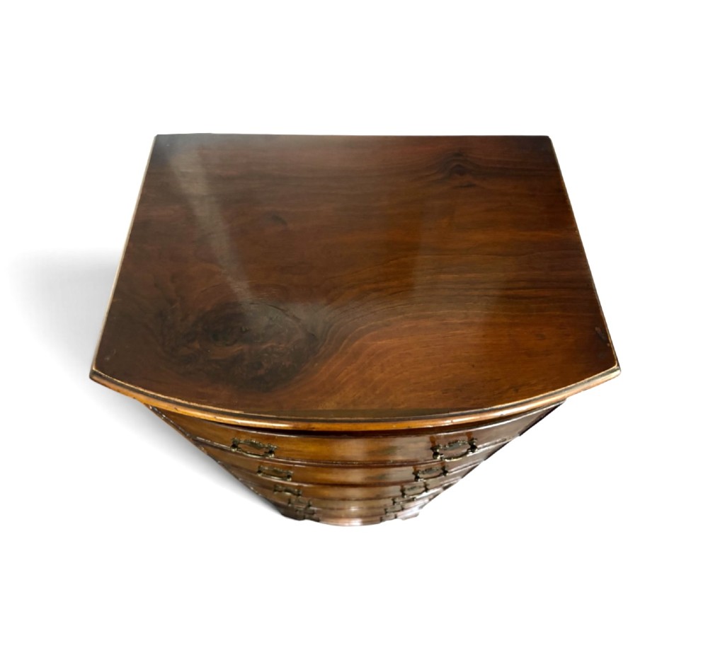 An early 20th-century figured walnut bow-front tallboy featuring six stacked drawers with brass bail handles and bracket feet. View IV