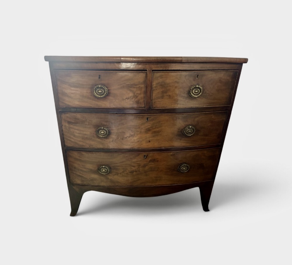 A Regency mahogany bowfront chest of drawers featuring two short drawers over two long drawers with brass ring handles and splayed feet.