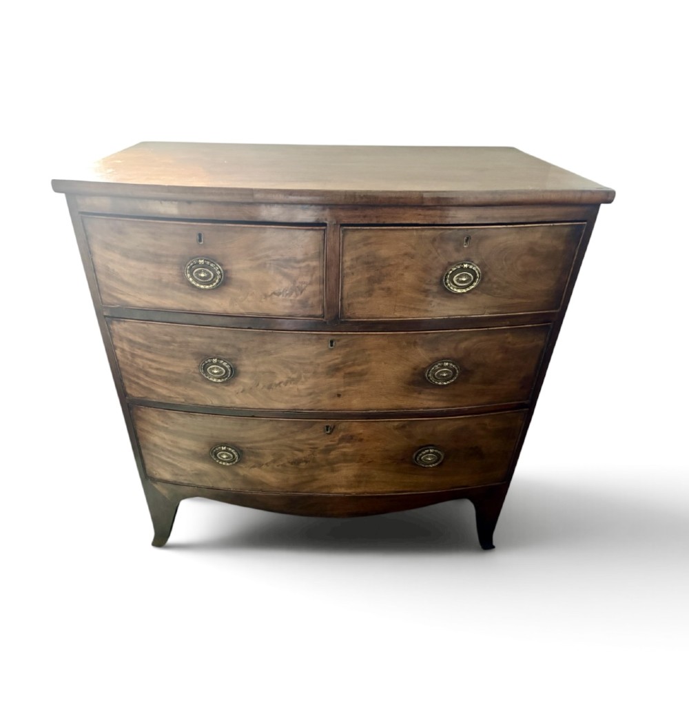 A Regency mahogany bowfront chest of drawers featuring two short drawers over two long drawers with brass ring handles and splayed feet. View III