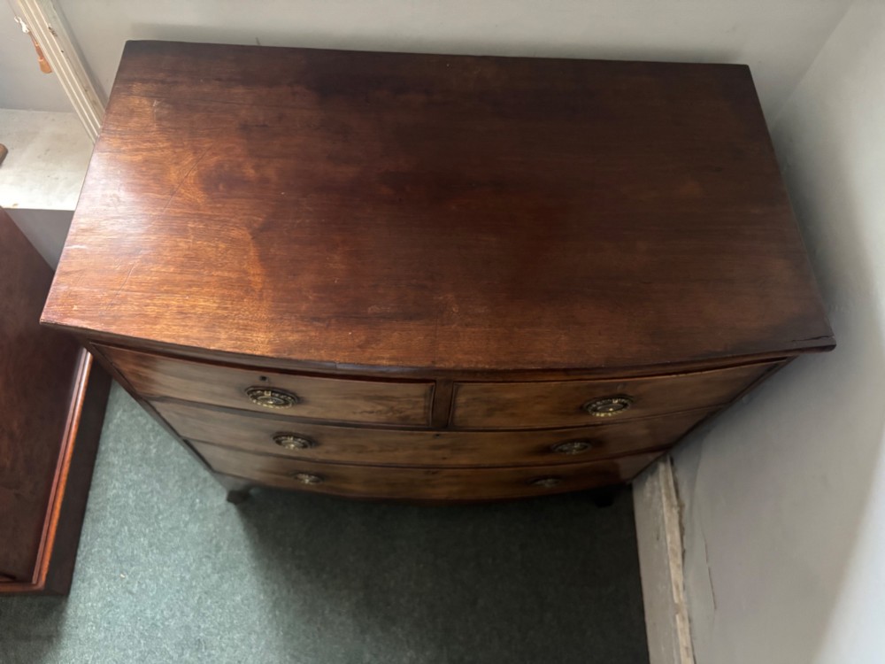 A Regency mahogany bowfront chest of drawers featuring two short drawers over two long drawers with brass ring handles and splayed feet. View VIII