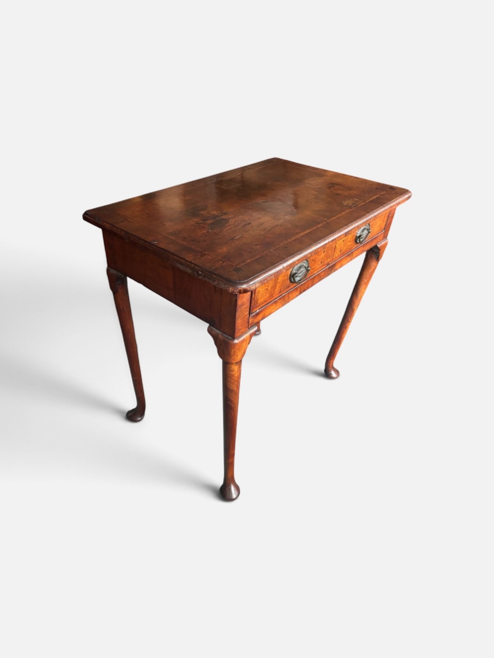 A George III walnut lowboy featuring a crossbanded top, a drawer with brass handles, and slender cabriole legs terminating in pad feet. View II