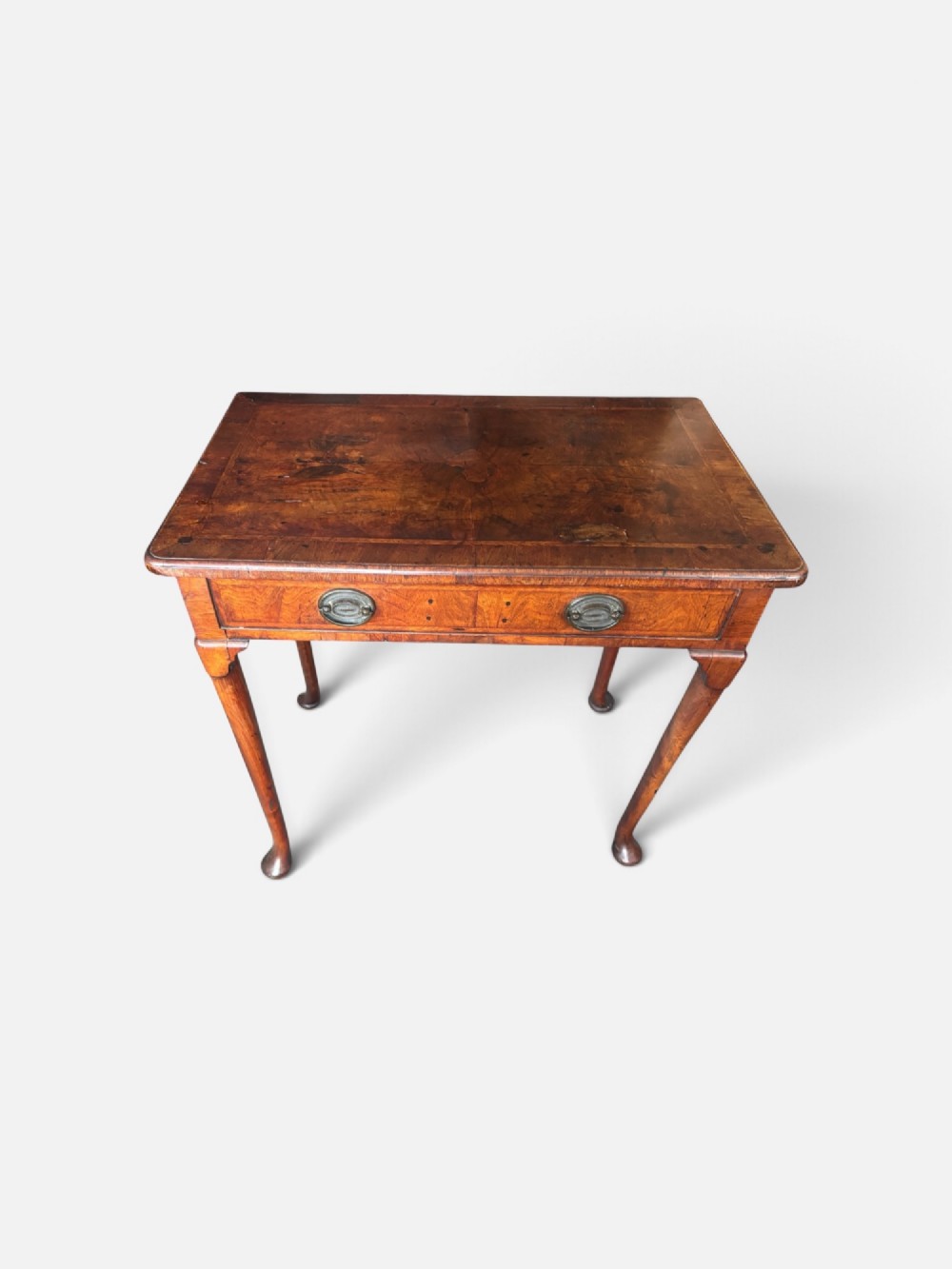 A George III walnut lowboy featuring a crossbanded top, a drawer with brass handles, and slender cabriole legs terminating in pad feet. View V