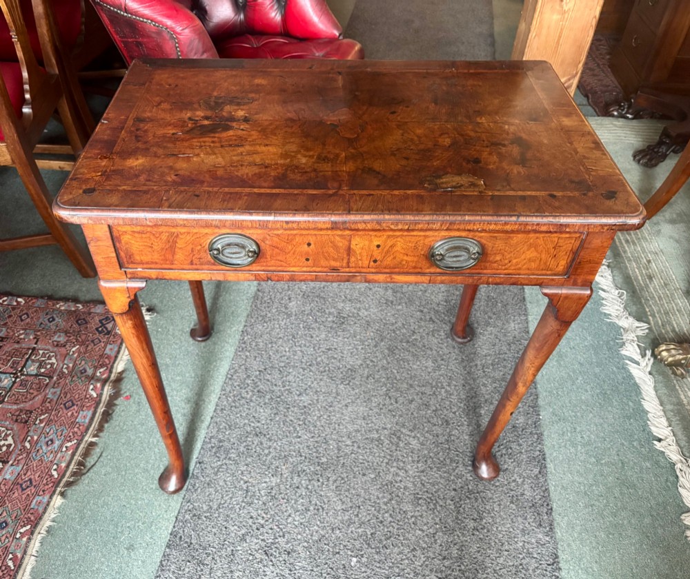A George III walnut lowboy featuring a crossbanded top, a drawer with brass handles, and slender cabriole legs terminating in pad feet. View X