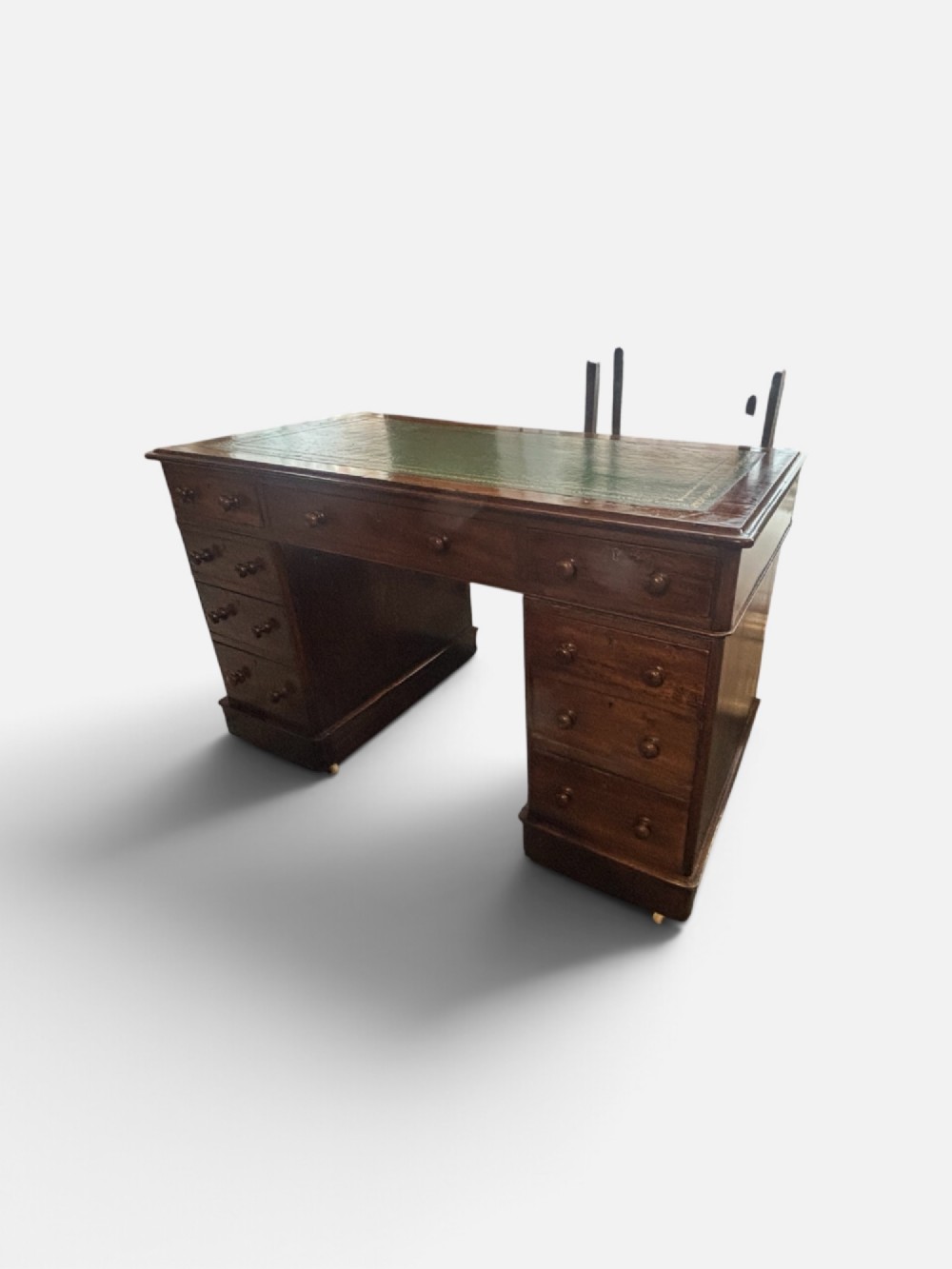 A Victorian mahogany pedestal desk featuring a green gilt-tooled leather writing surface, nine drawers with turned wooden knobs, and a central kneehole. View II