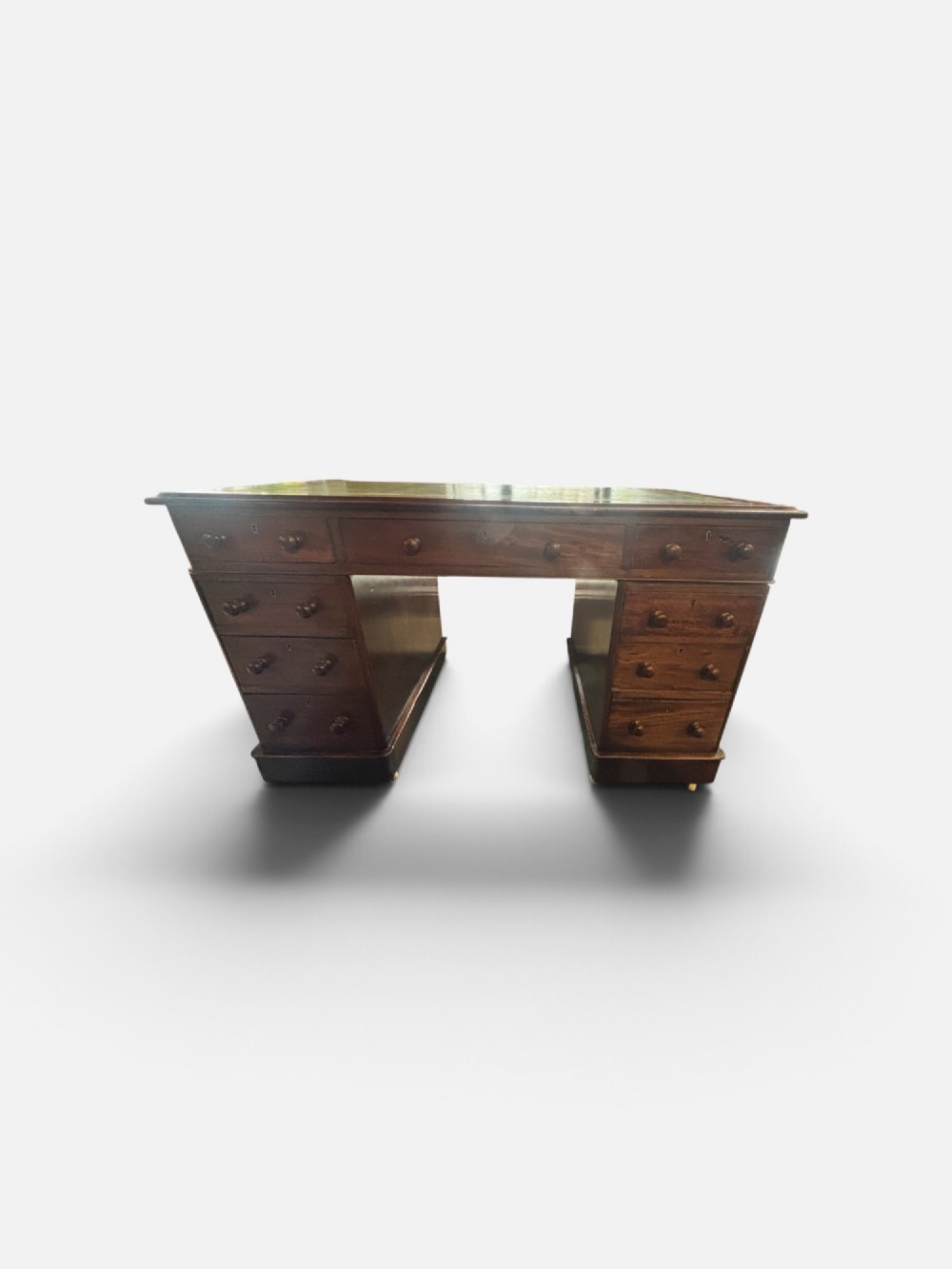 A Victorian mahogany pedestal desk featuring a green gilt-tooled leather writing surface, nine drawers with turned wooden knobs, and a central kneehole. View IV