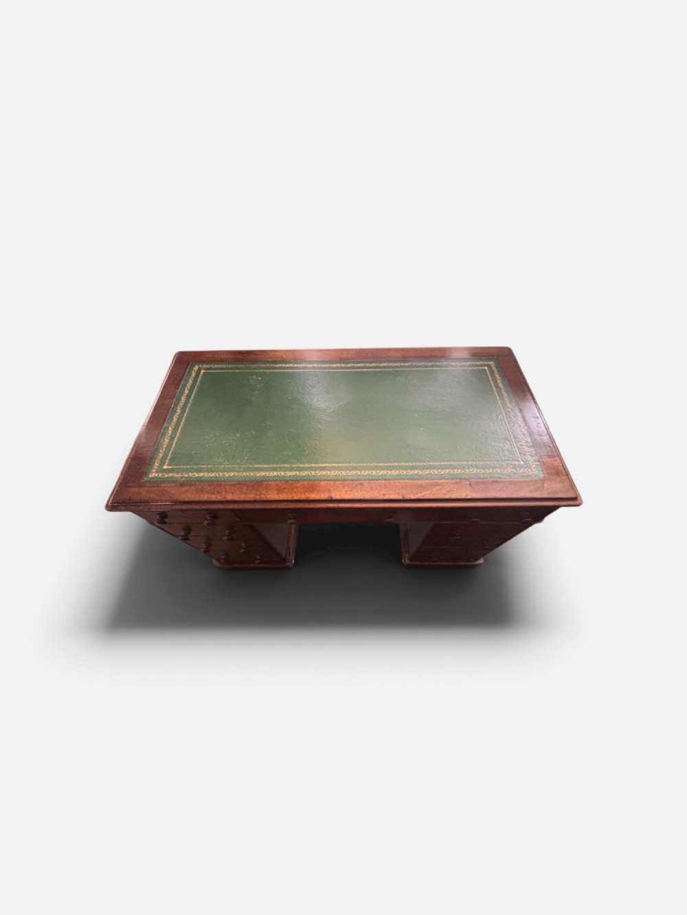 A Victorian mahogany pedestal desk featuring a green gilt-tooled leather writing surface, nine drawers with turned wooden knobs, and a central kneehole. View V