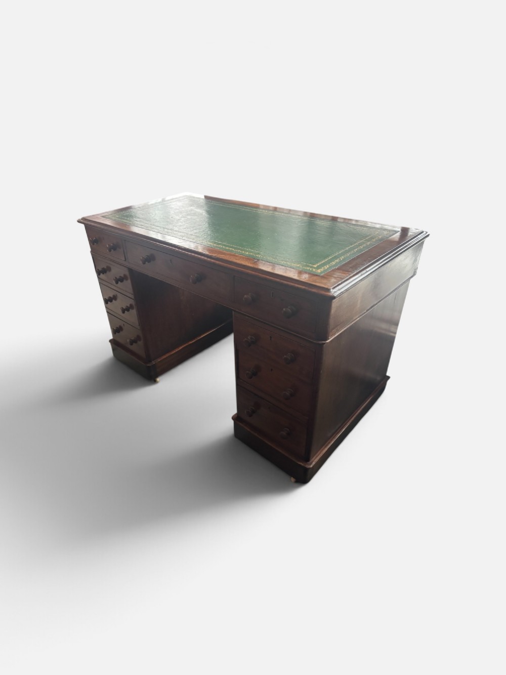 A Victorian mahogany pedestal desk featuring a green gilt-tooled leather writing surface, nine drawers with turned wooden knobs, and a central kneehole. View VI