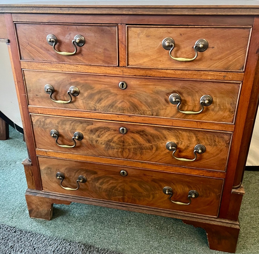 An Edwardian mahogany chest of drawers with two short drawers over three long drawers, brass swan-neck handles, and bracket feet. View V