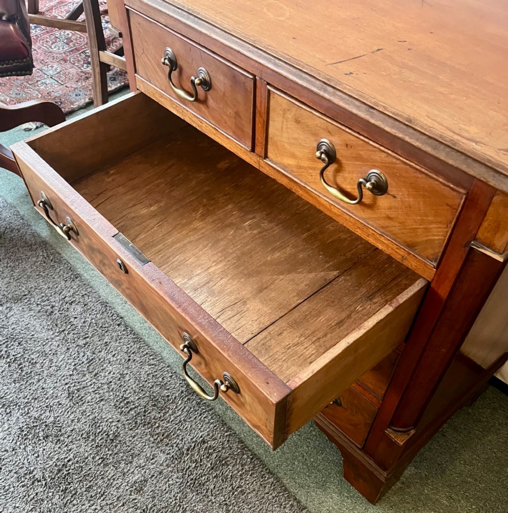 An Edwardian mahogany chest of drawers with two short drawers over three long drawers, brass swan-neck handles, and bracket feet. View VI