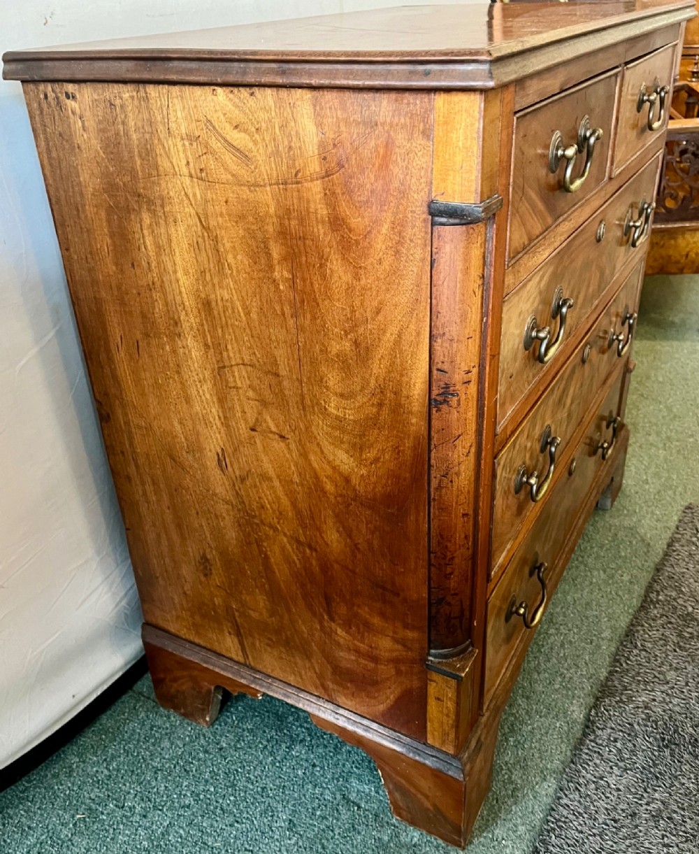 An Edwardian mahogany chest of drawers with two short drawers over three long drawers, brass swan-neck handles, and bracket feet. View VII