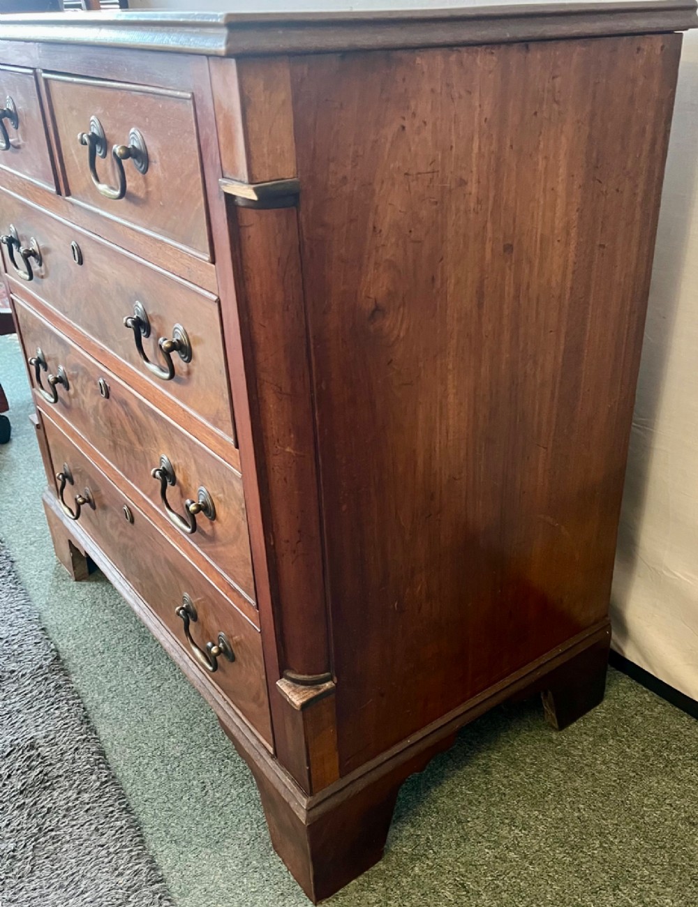An Edwardian mahogany chest of drawers with two short drawers over three long drawers, brass swan-neck handles, and bracket feet. View VIII